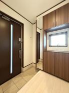 玄関　たっぷりと収納できるシューズボックスを備えた窓のある明るい玄関内。